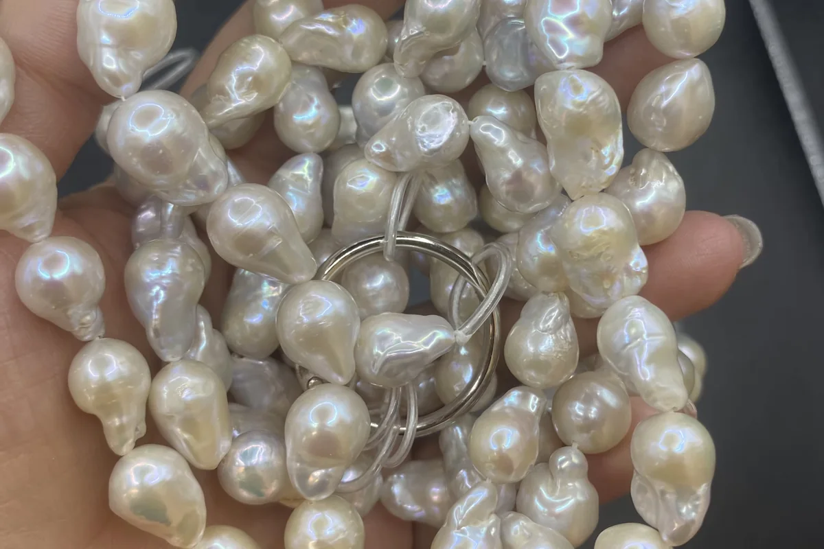 Hand holding strands of irregular white baroque pearls