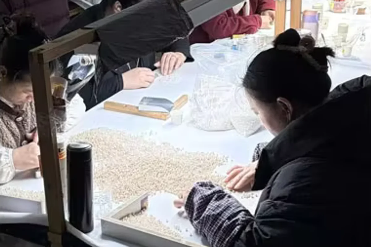 Workers examining white pearls under task lighting