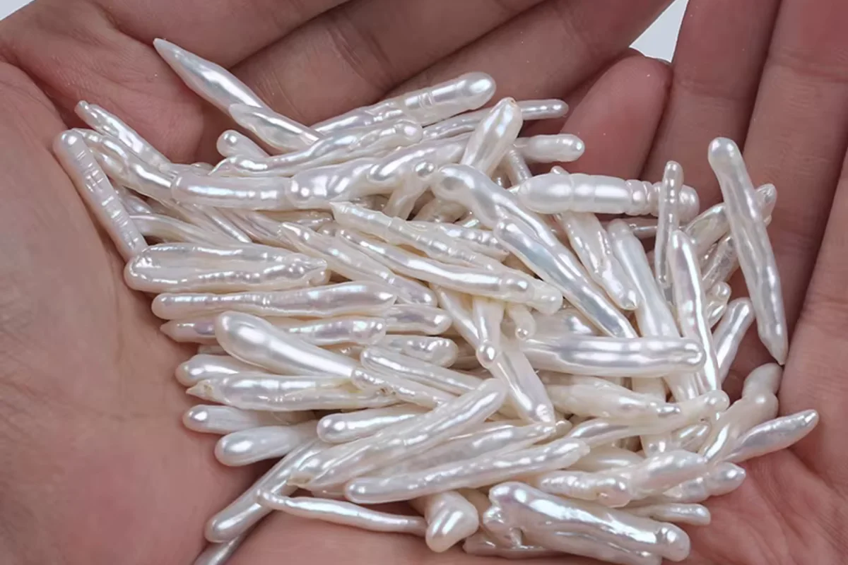 Hands holding loose elongated white pearls