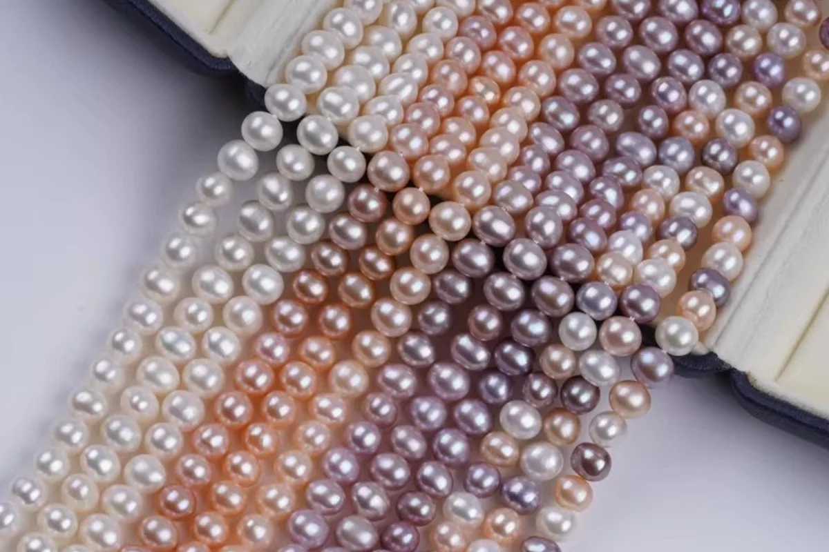 White, peach and lavender pearl strands draped across an open box.