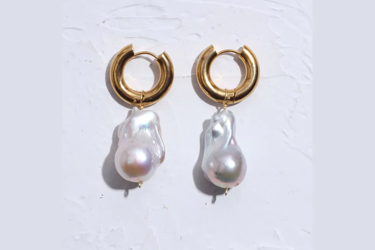White baroque pearl drops attached to gold-colored hoop earrings with small metal loops.