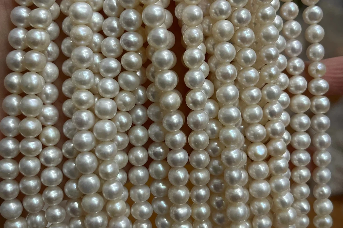 Rows of white pearl strands held together in a hand.