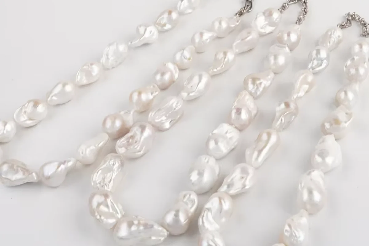 Several white baroque pearl necklaces arranged in parallel rows.
