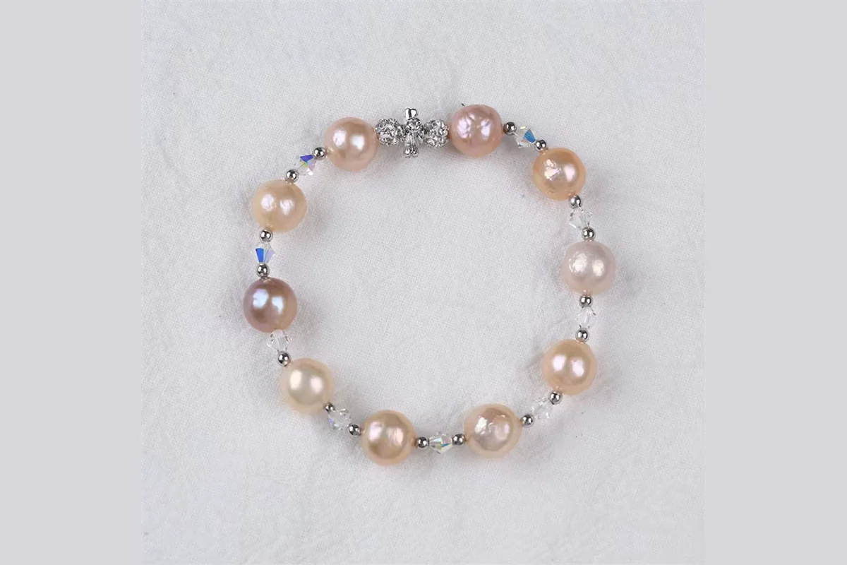 A bracelet with peach, pink and cream pearls and small clear beads.
