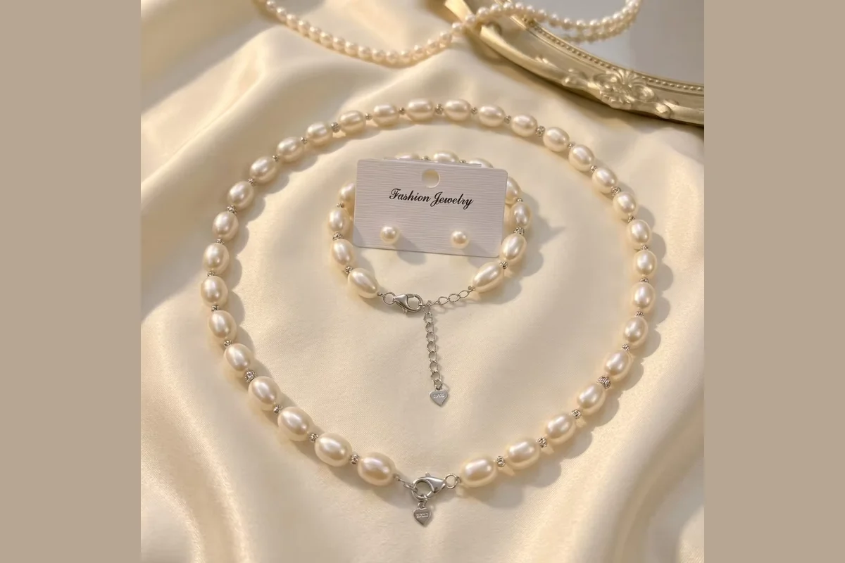 A pearl necklace and bracelet beside earrings on a display card.