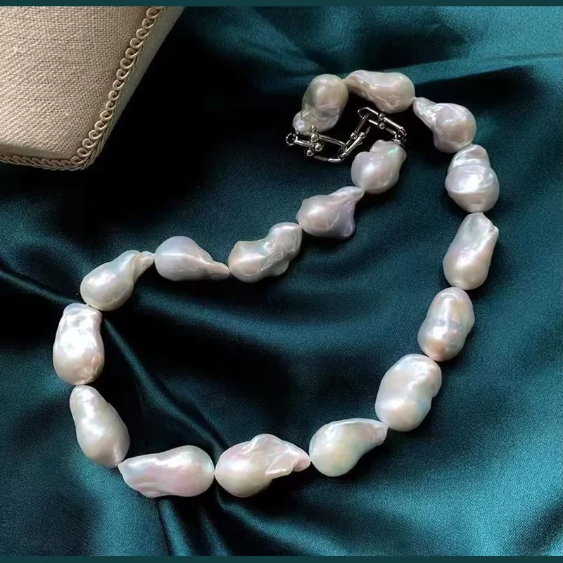 Short necklace of large irregular white pearls on dark teal satin