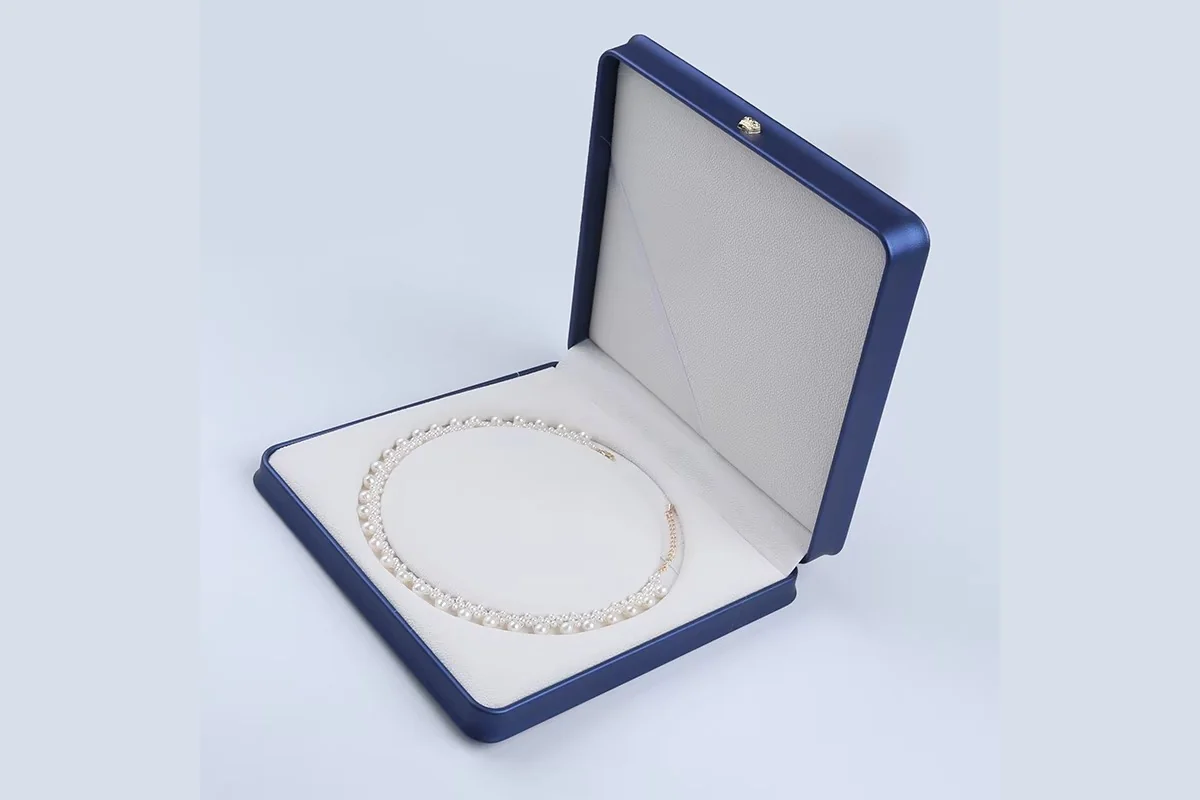 A white pearl necklace presented inside an open blue jewelry box