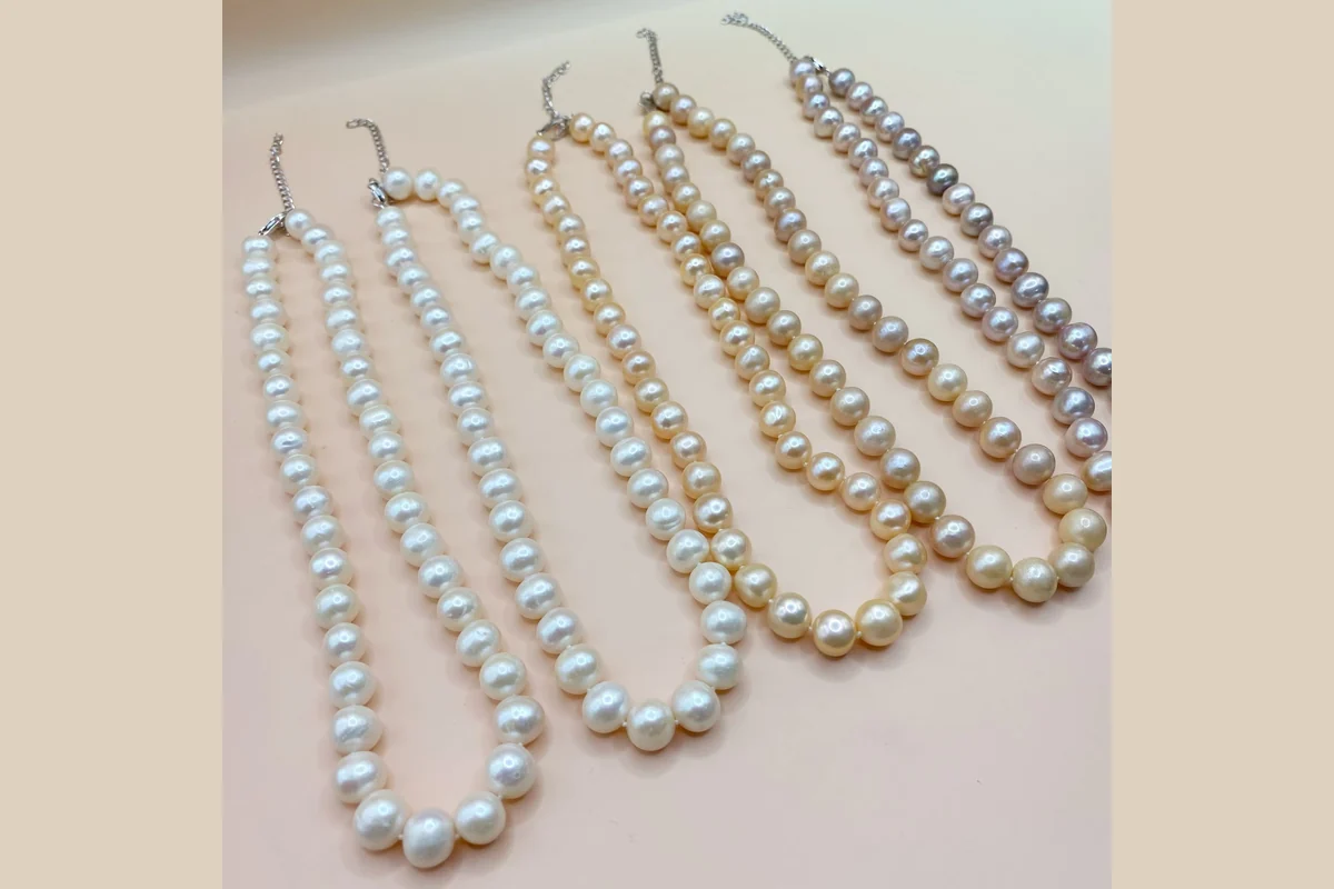 White, peach and lavender pearl strand necklaces arranged side by side