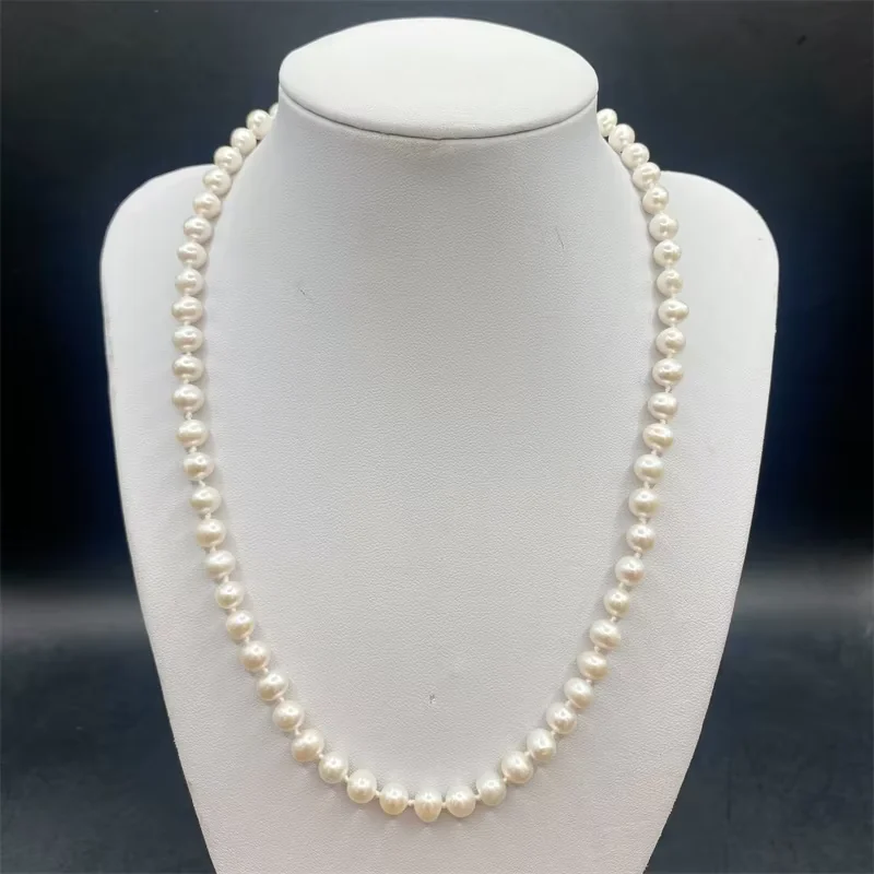 Single white pearl strand necklace on a pale jewelry bust