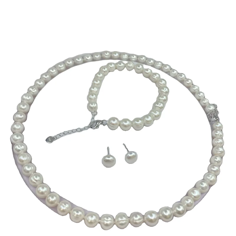 A white pearl necklace, bracelet and stud earring set on white.