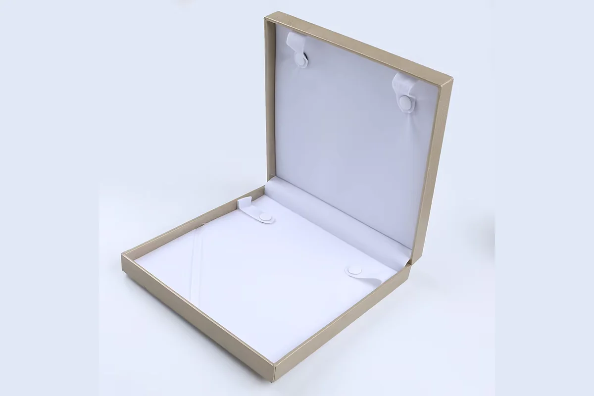 An open cream jewelry box with a white necklace insert.