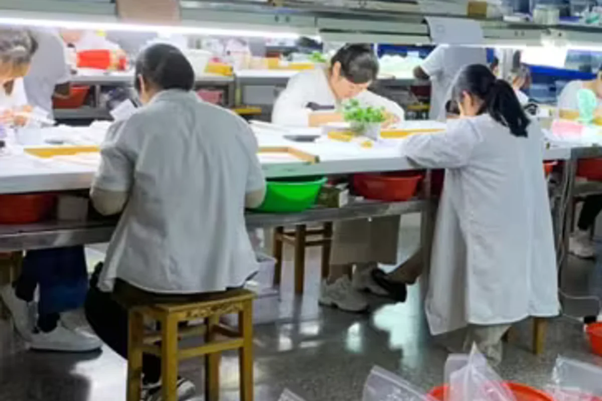 Workers seated at pearl processing workbenches.