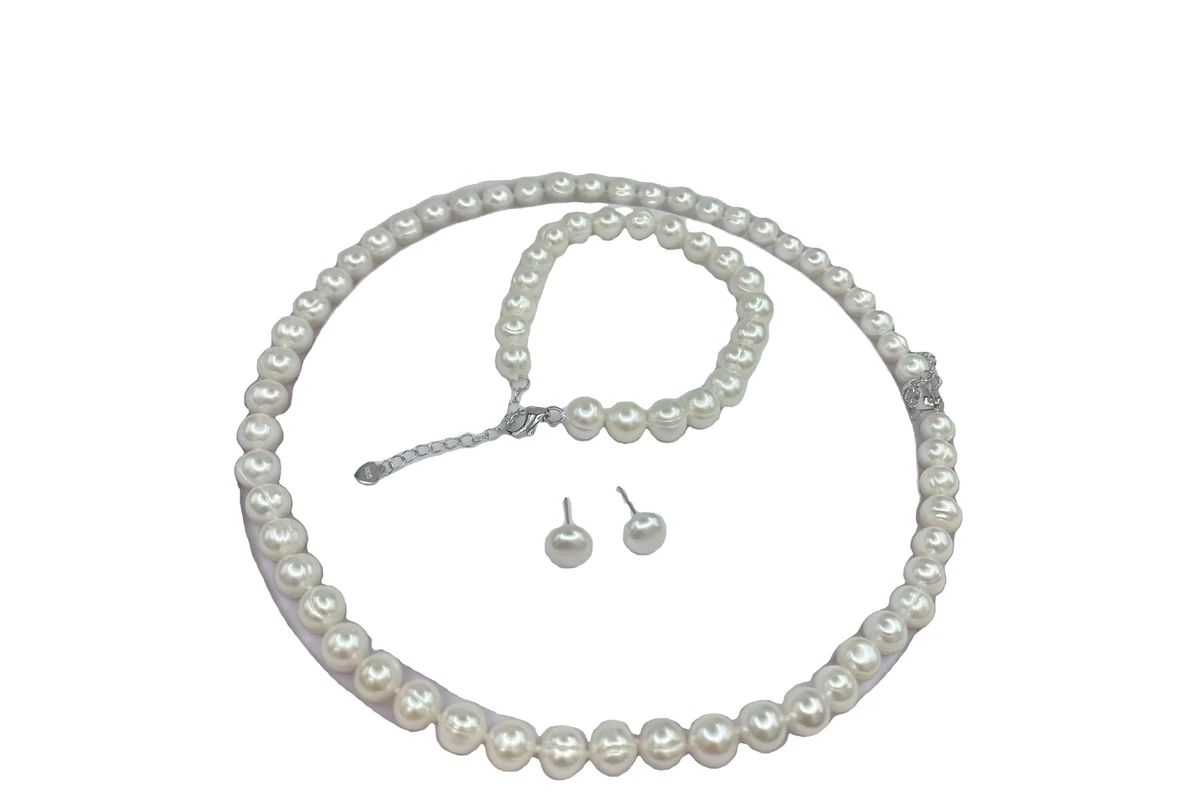White pearl necklace, bracelet and stud earrings arranged together