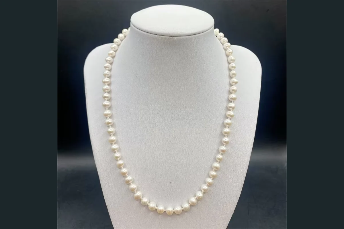 White pearl strand necklace displayed on a pale jewelry bust
