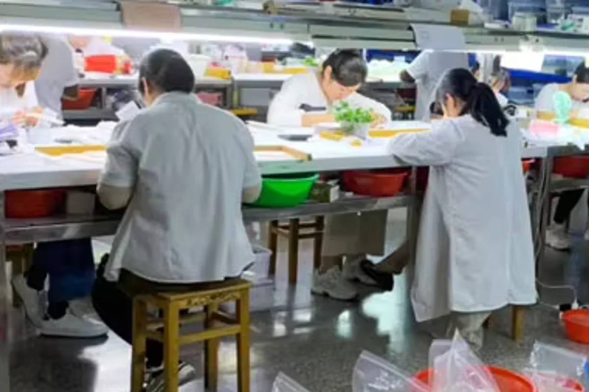 Workers seated at pearl processing workbenches