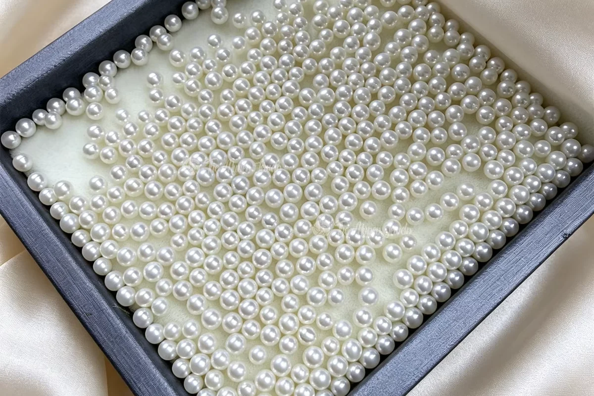 Rows of loose white pearls arranged in a dark tray