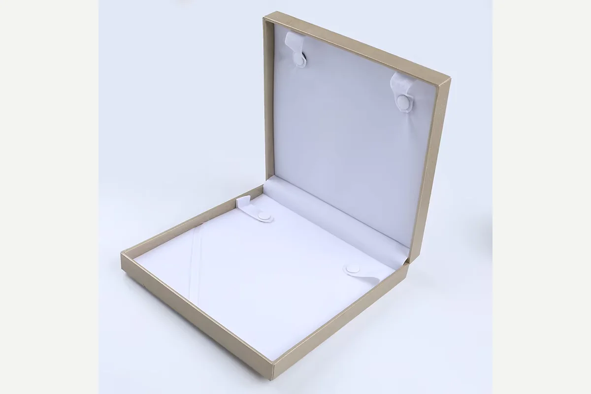 An open cream jewelry box with a white necklace insert